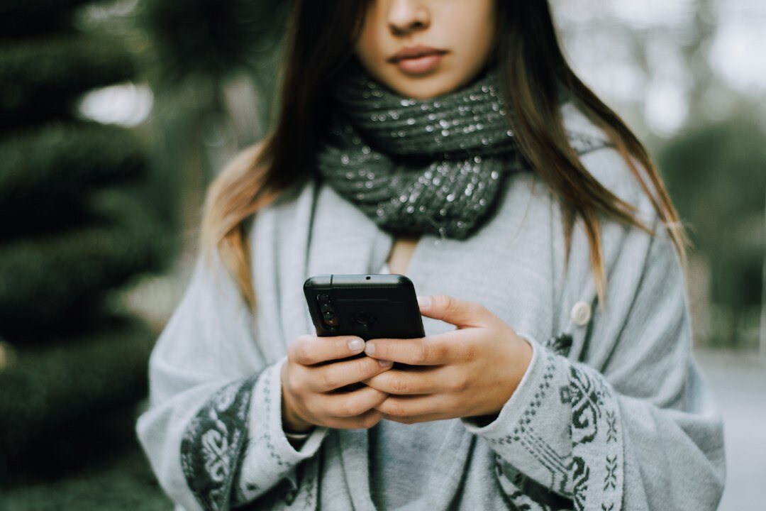 Jovem brasileira lendo um artigo no celular enquanto relaxa em um sofá